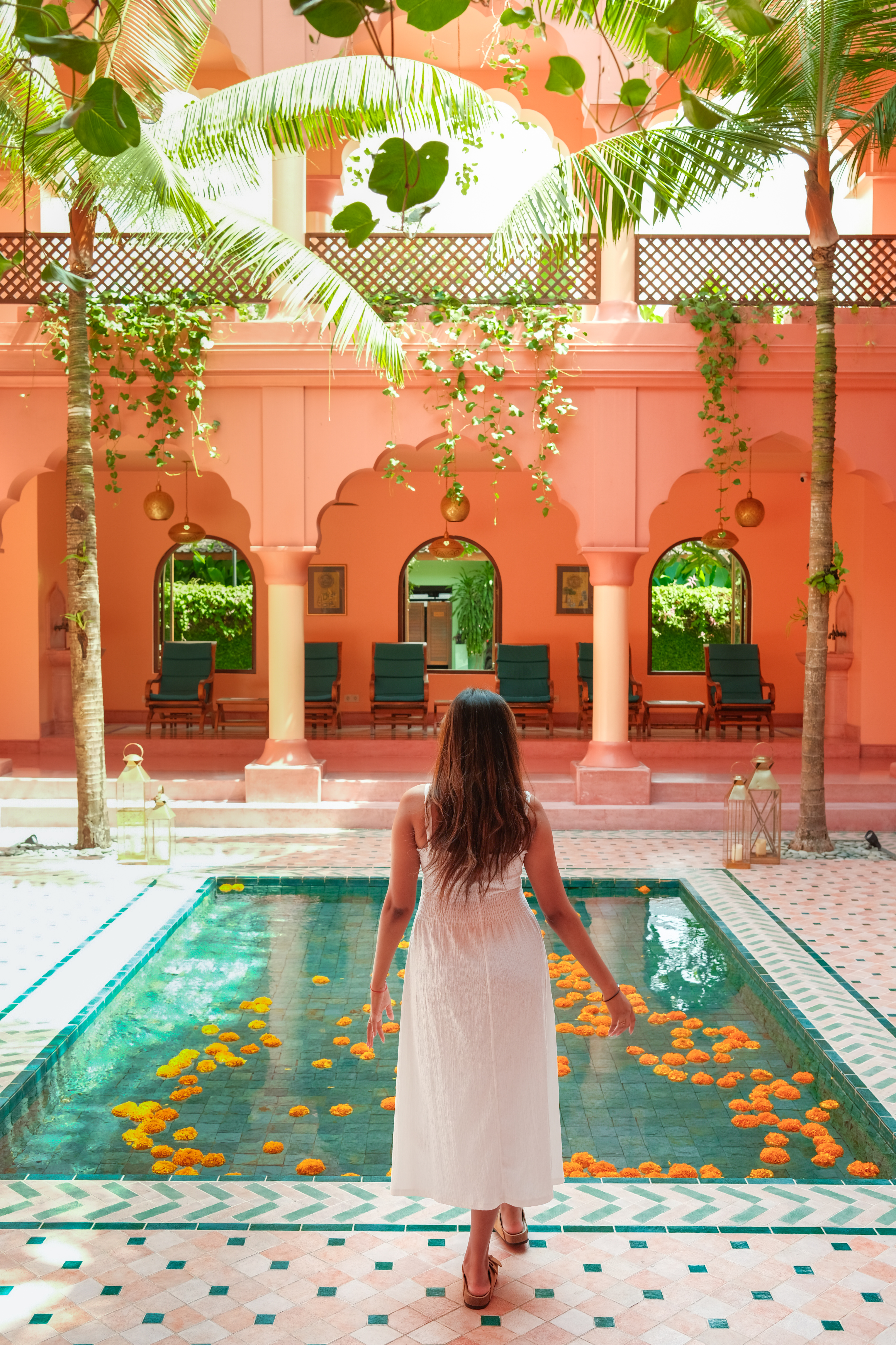Figure beside a floral pool in a pink courtyard